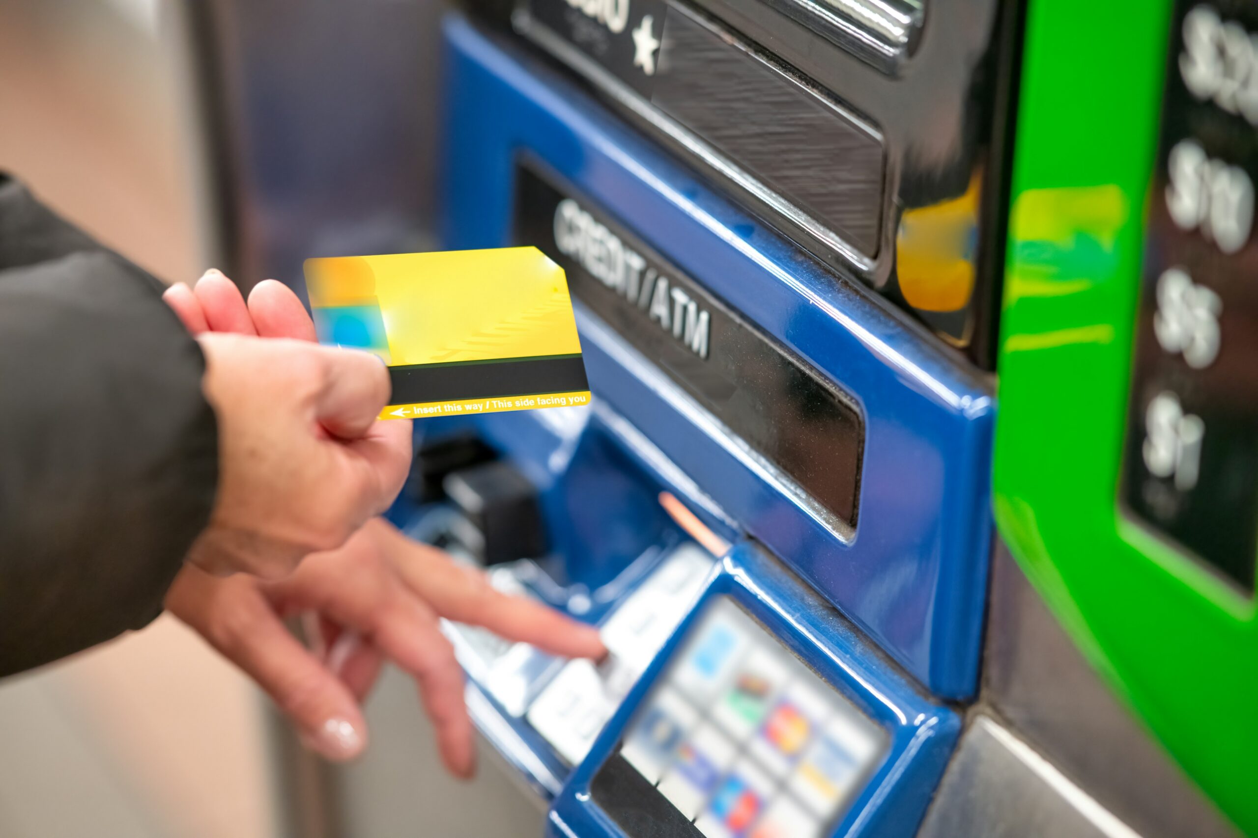 Person inserting credit card into ATM machine for cash withdrawal